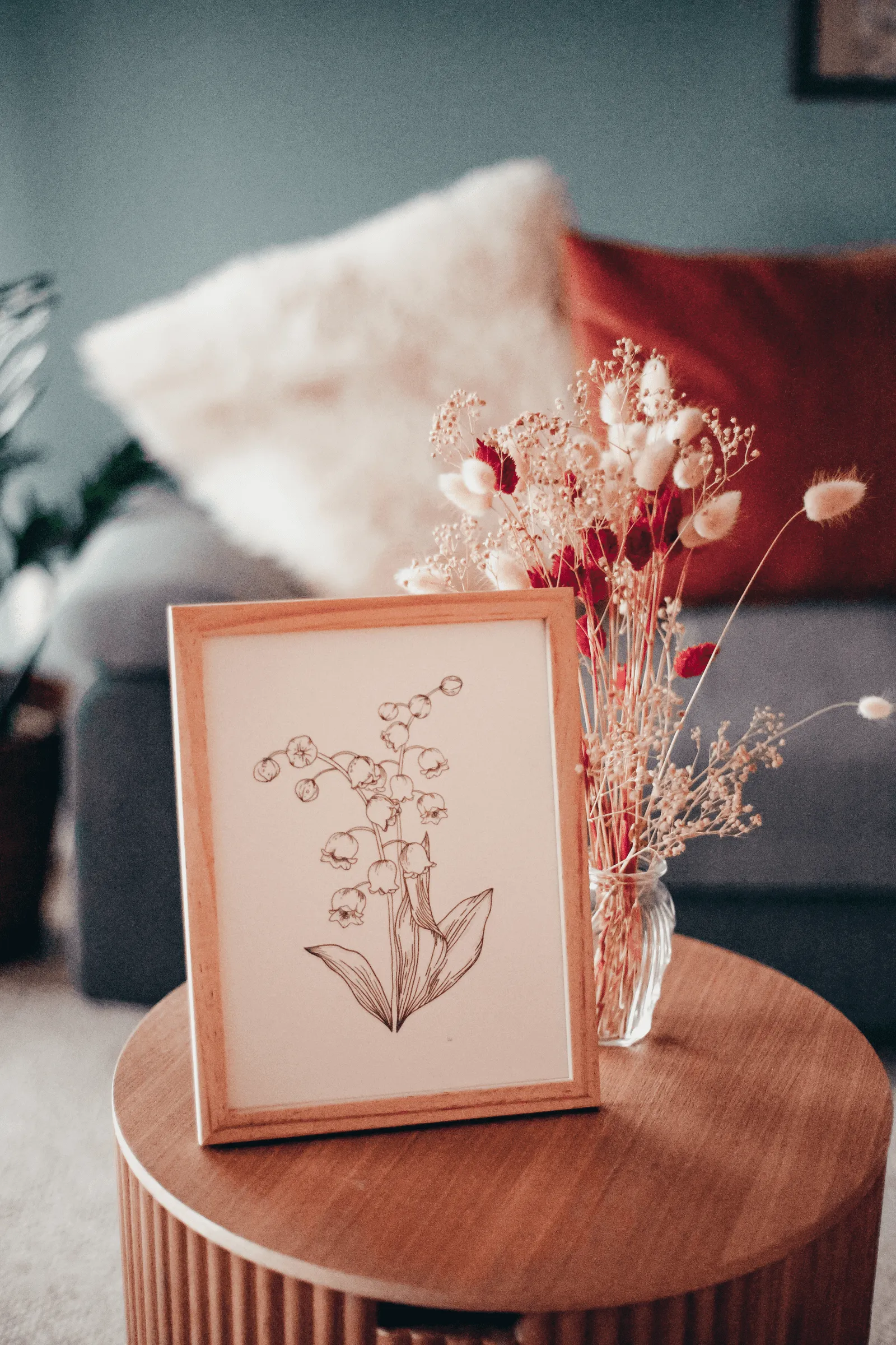 Cadre avec dessin de muguet imprimé et bouquet de fleurs séchées dans un salon