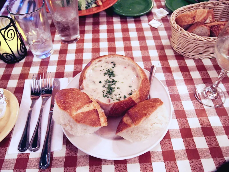Clam chowder servie dans un pain rond sur une nappe à carreaux rouges