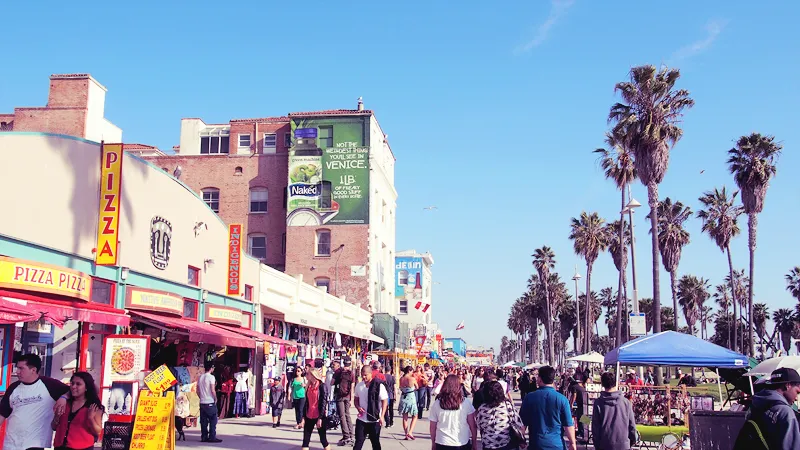 Foule sur la promenade de Venice Beach entre boutiques et palmiers