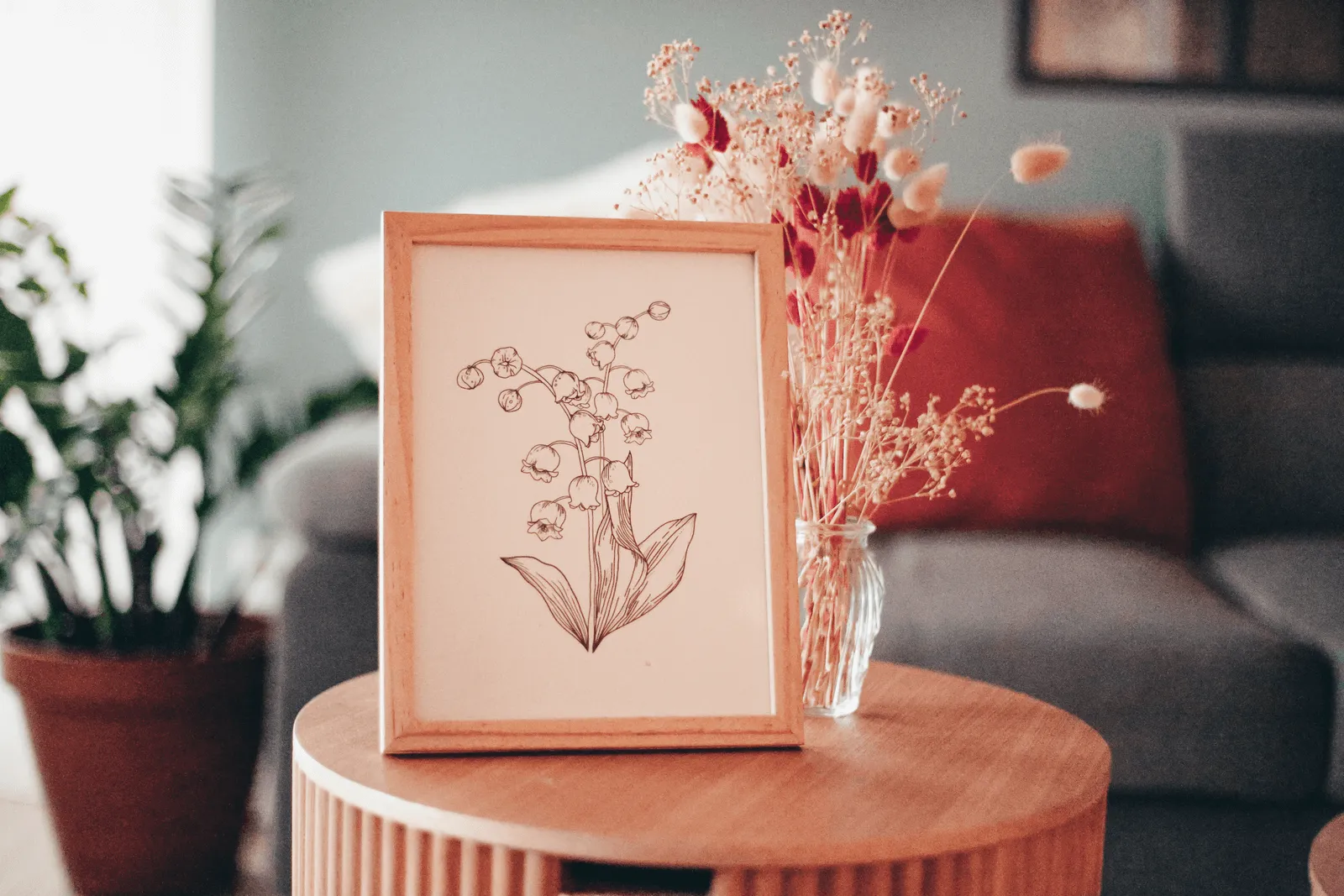Illustration de brin de muguet à imprimer encadrée sur une table d'appoint avec fleurs séchées