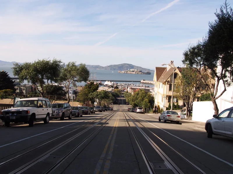 Rue en pente de Hyde Street avec rails de cable car et Alcatraz au loin