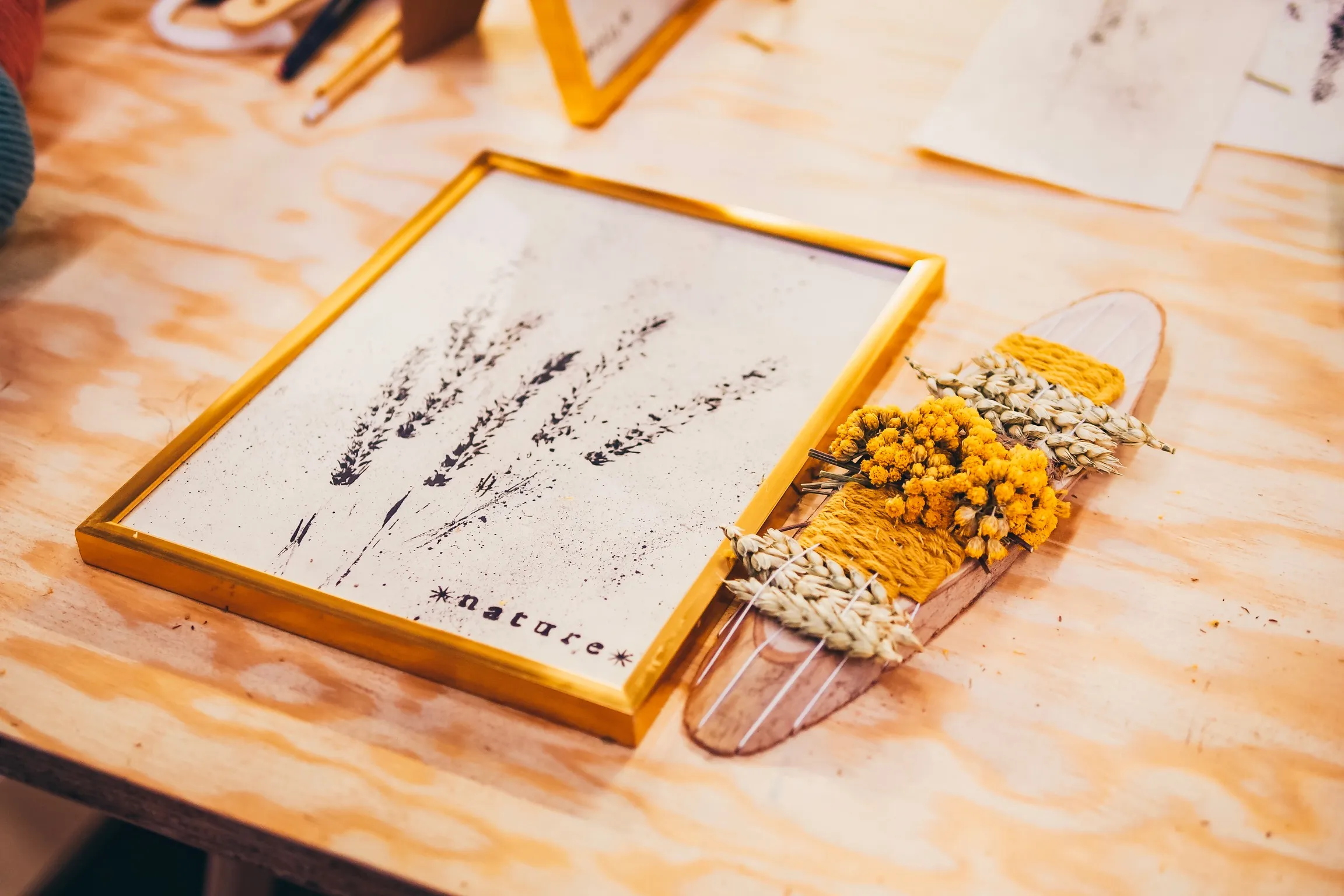 Tableau végétal à empreintes de lavande et totem en fleurs séchées sur un plan de travail en bois
