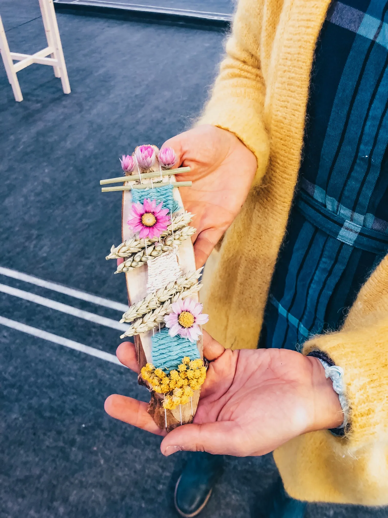 Totem végétal DIY décoré de fleurs séchées et de laine colorée tenu à la main