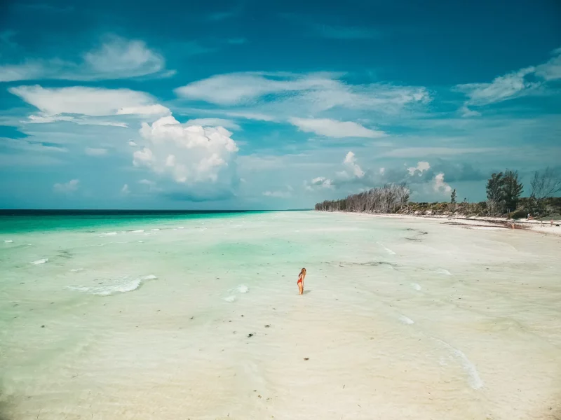 Voyageuse marchant dans l'eau peu profonde d'une immense plage turquoise de Grand Bahama